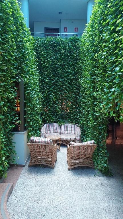 three wicker chairs and a couch in front of a hedge at Pousada dos Girassóis in Palmas