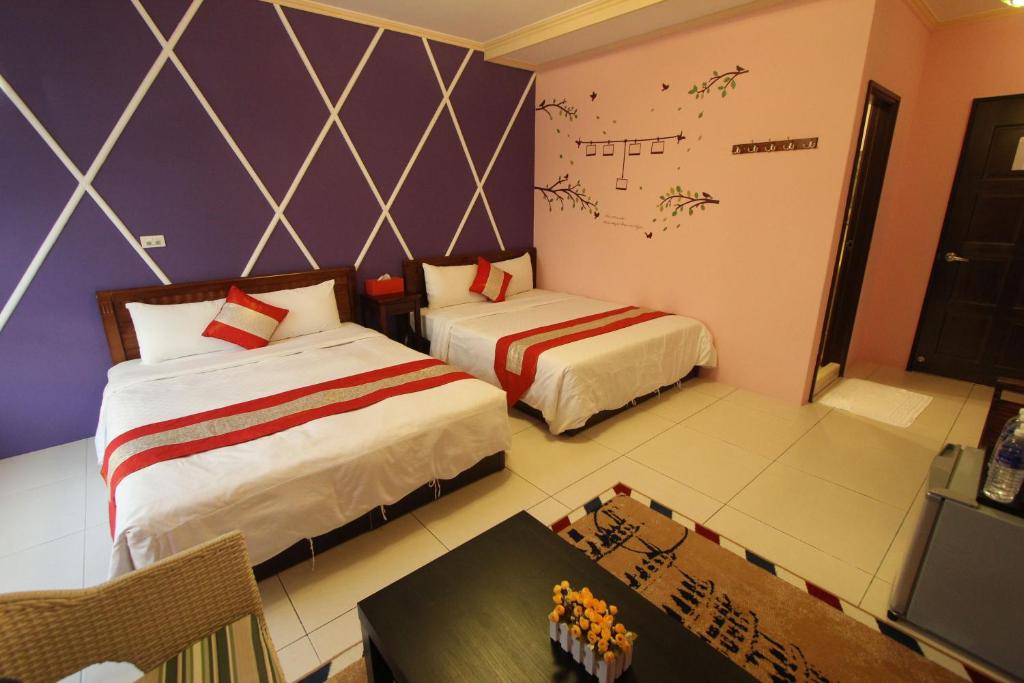 a bedroom with two beds and a table and a desk at Kenting Diack Inn in Hengchun South Gate