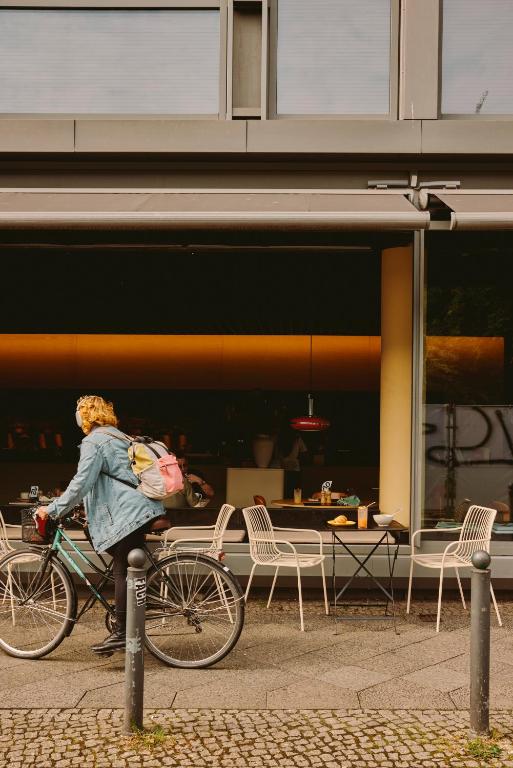 a woman riding a bike in front of a restaurant at Casa Camper Berlin in Berlin