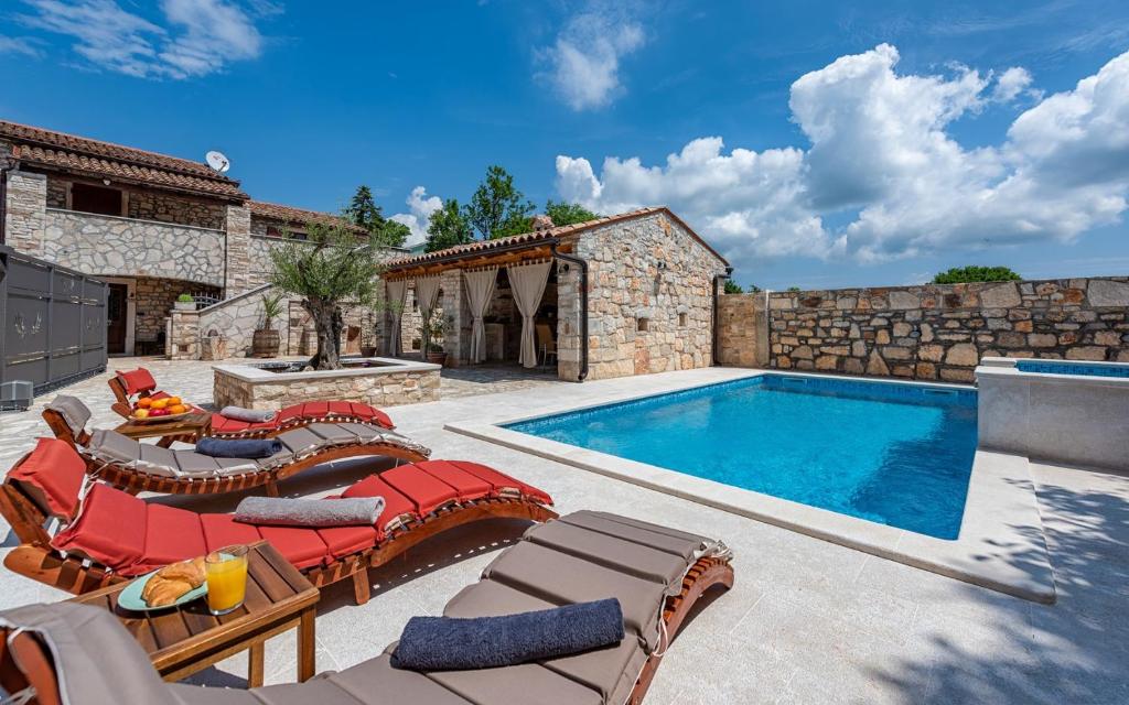 a swimming pool with patio furniture and a villa at Rustic stone holiday house with pool in Marčana