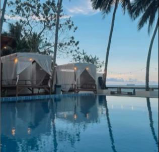 a swimming pool with two tents and palm trees at Kopap Villa in Lalonggasumeto