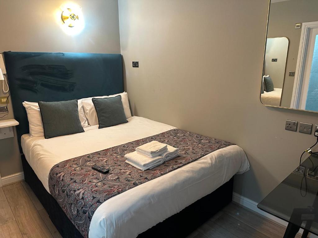 a small bedroom with a bed with a mirror at Arran House Hotel in London