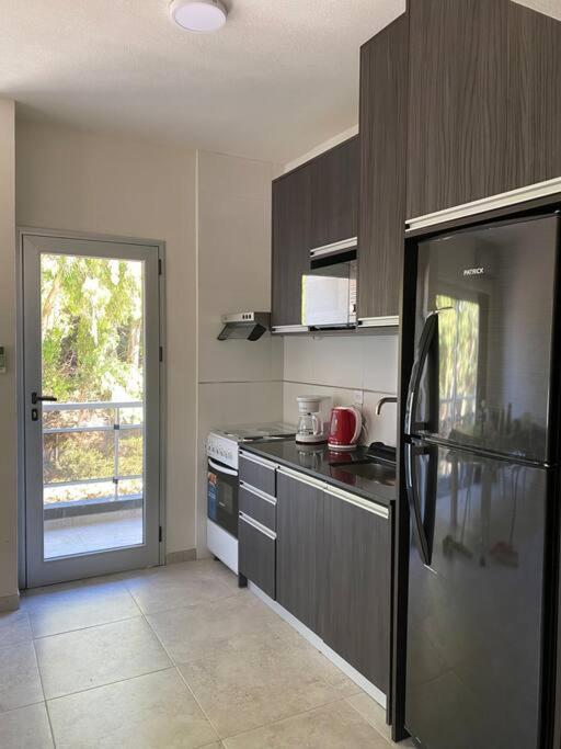 a kitchen with a stainless steel refrigerator and a window at Departamento Pinamar centro Jupiter in Pinamar