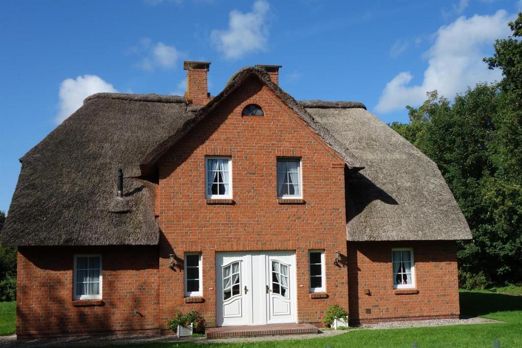 an old brick house with a thatched roof at Haushälfte Luv und Lee in Tating