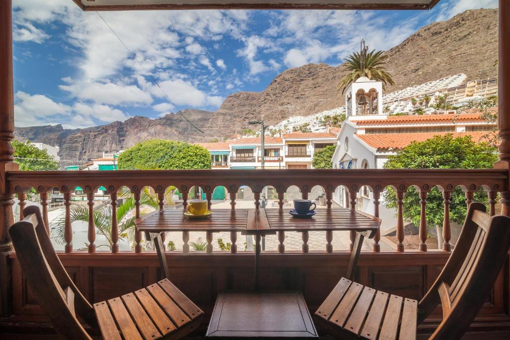 Una mesa y sillas en un balcón con montañas al fondo. en PARAISO BAMBOO - 2 bedrooms, 2 bathrooms, fibre net, heart of the Los Gigantes, tv channels, en Acantilado de los Gigantes