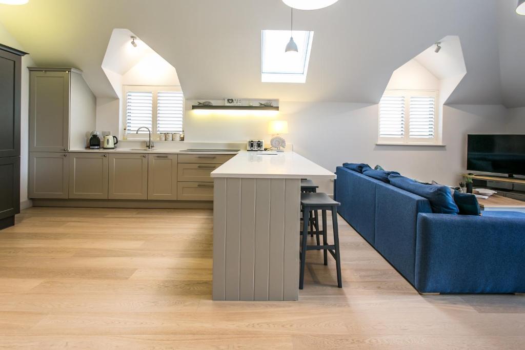 a kitchen and living room with a blue couch at Seashells Bracklesham Bay in Chichester