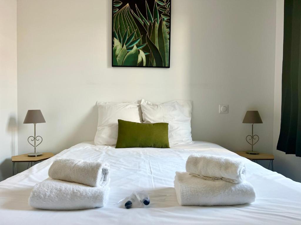 ein weißes Bett mit zwei Handtüchern darauf in der Unterkunft L'Oasis, Appartement Confort, Centre-ville in La Tremblade