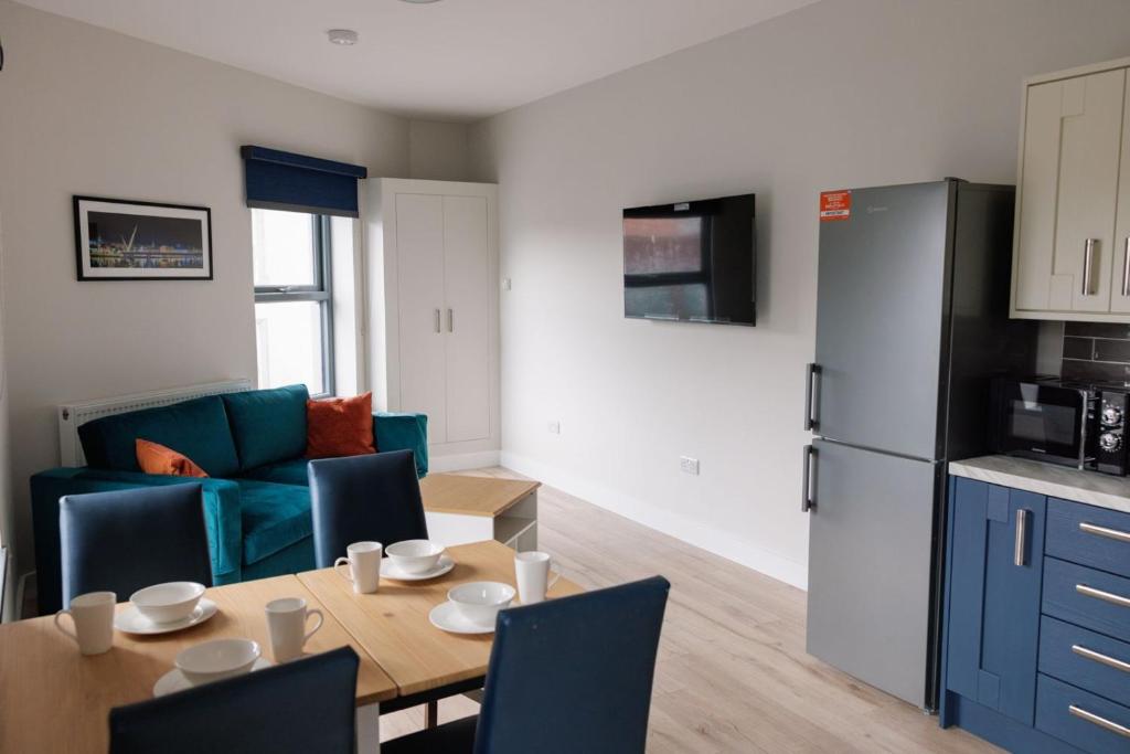 een keuken en een woonkamer met een tafel en een koelkast bij River Walk Apartments in Derry Londonderry