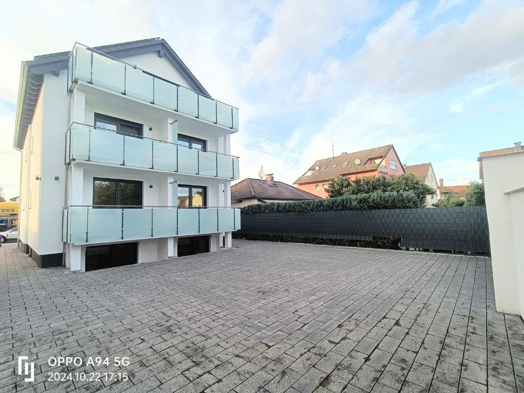 a white building with blue balconies on a street at Deluxe Studio-Apartments in Mörfelden-Walldorf
