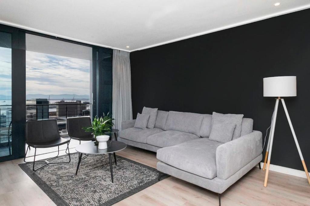 a living room with a couch and a table and chairs at 16 on Bree Modern 2BR Luxury Apartment in Cape Town