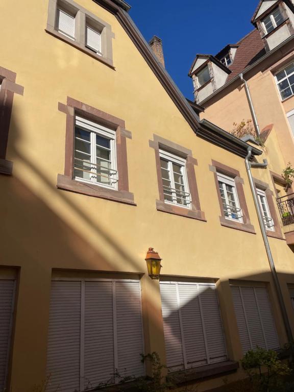 a yellow building with shuttered windows and a street light at LE PIERRE 2 CH 2 SDB 1 parking in Strasbourg