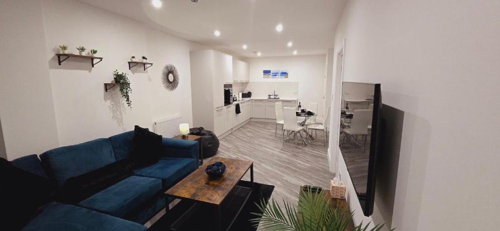 a living room with a blue couch and a table at Abbey Corner by Nivaas 2-Located in the heart of the city centre-5 minute walk to train station-20 minutes to London via train in Reading