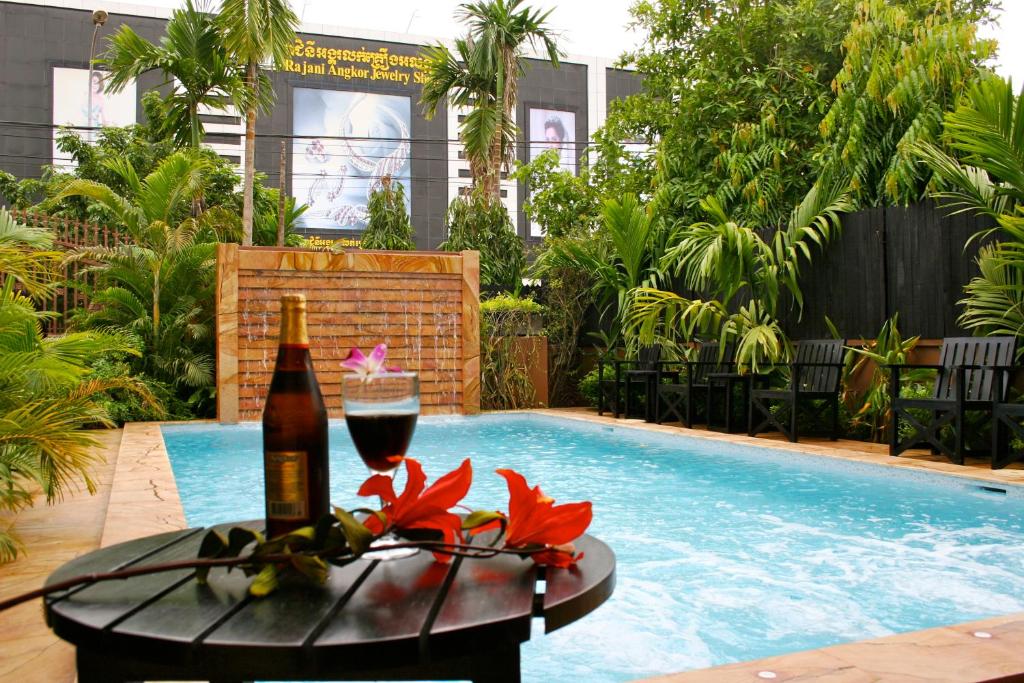 a bottle of wine and a glass next to a swimming pool at Shining Angkor Boutique Hotel in Siem Reap