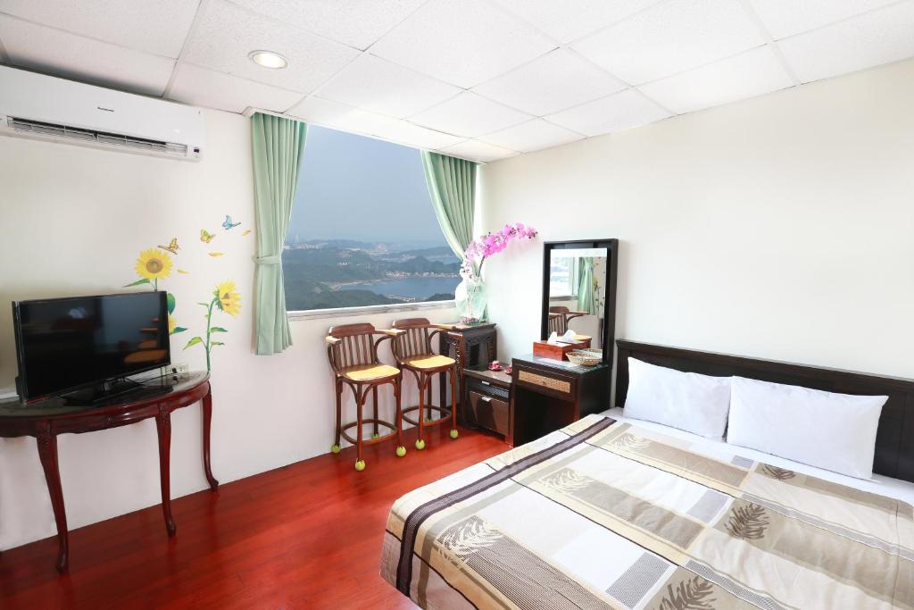 a bedroom with a bed and a desk and a television at Yuan-Yee Homestay in Jiufen