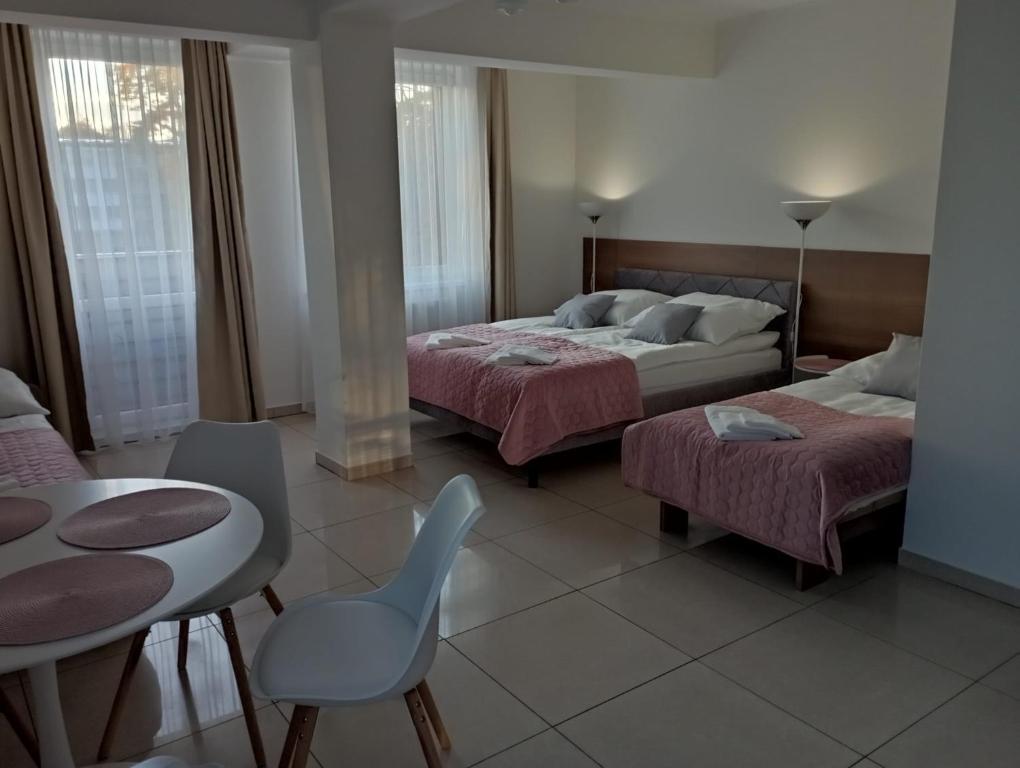 a bedroom with two beds and a table and chairs at Apartamenty Planeta 105, 108 Mielno - parking w cenie pobytu in Mielno