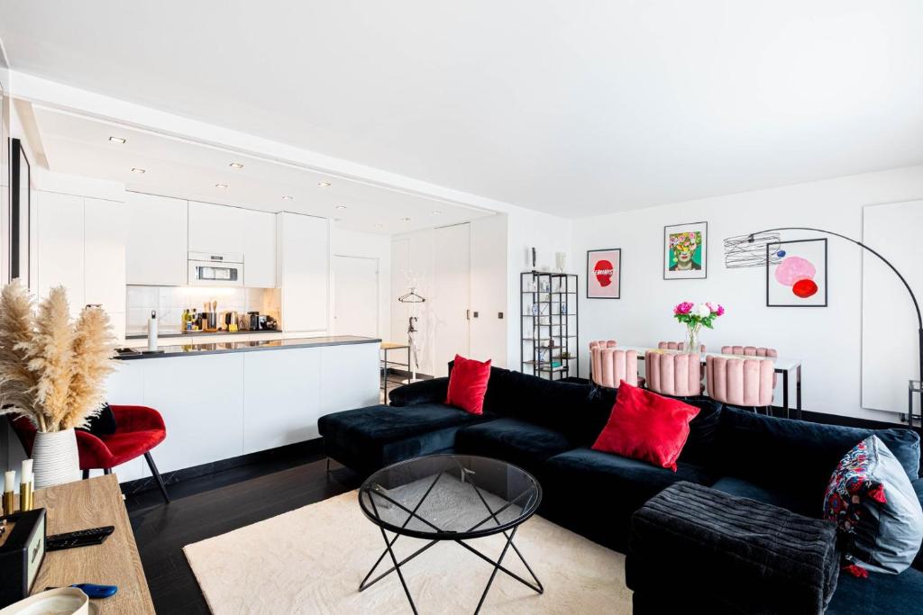 - un salon avec un canapé noir et des oreillers rouges dans l'établissement GuestReady - View of the Eiffel Tower ideal for 2, à Paris