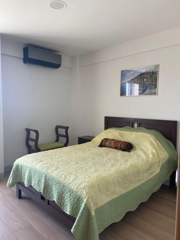 a bedroom with a bed with a green comforter at Departamento Cómodo in Tarija
