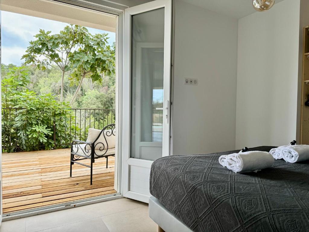a bedroom with a bed and a balcony with a chair at Villa Mare è Machja avec piscine et vue mer in Sari Solenzara