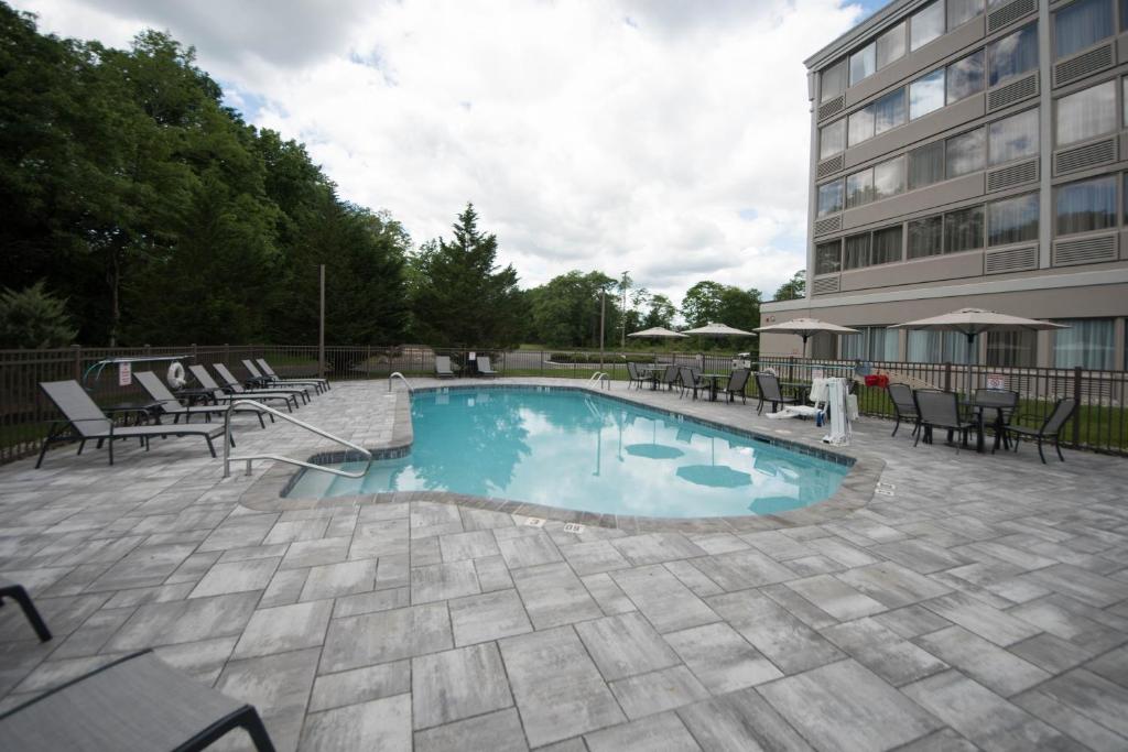 a swimming pool with chairs and a building at DoubleTree by Hilton Tinton Falls-Eatontown in Tinton Falls
