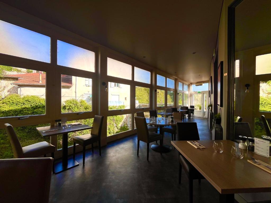restauracja ze stołami i krzesłami oraz dużymi oknami w obiekcie hotel restaurant le saint nazaire w mieście Saint-Nazaire-en-Royans