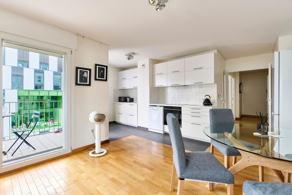 une cuisine et une salle à manger avec une table en verre dans l'établissement Charme Unique Terrasse & Parking proche Métro, à Paris