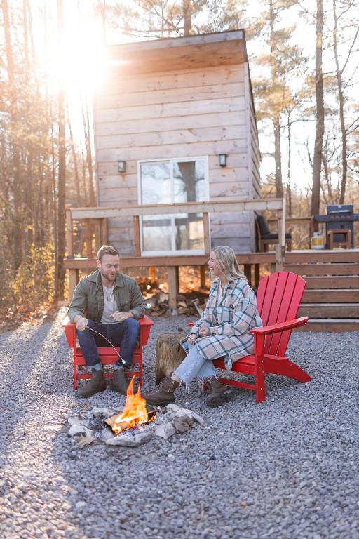 two people sitting around a fire in front of a cabin at The Green Acres Cabin in Hamilton