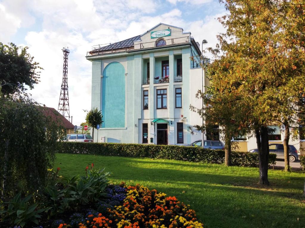 a blue and white building with flowers in a park at Hotel Ludza in Ludza