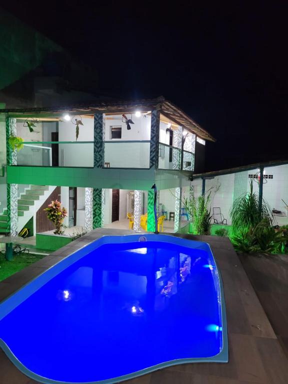 a house with a blue swimming pool at night at Casa Aconchegante in Anchieta