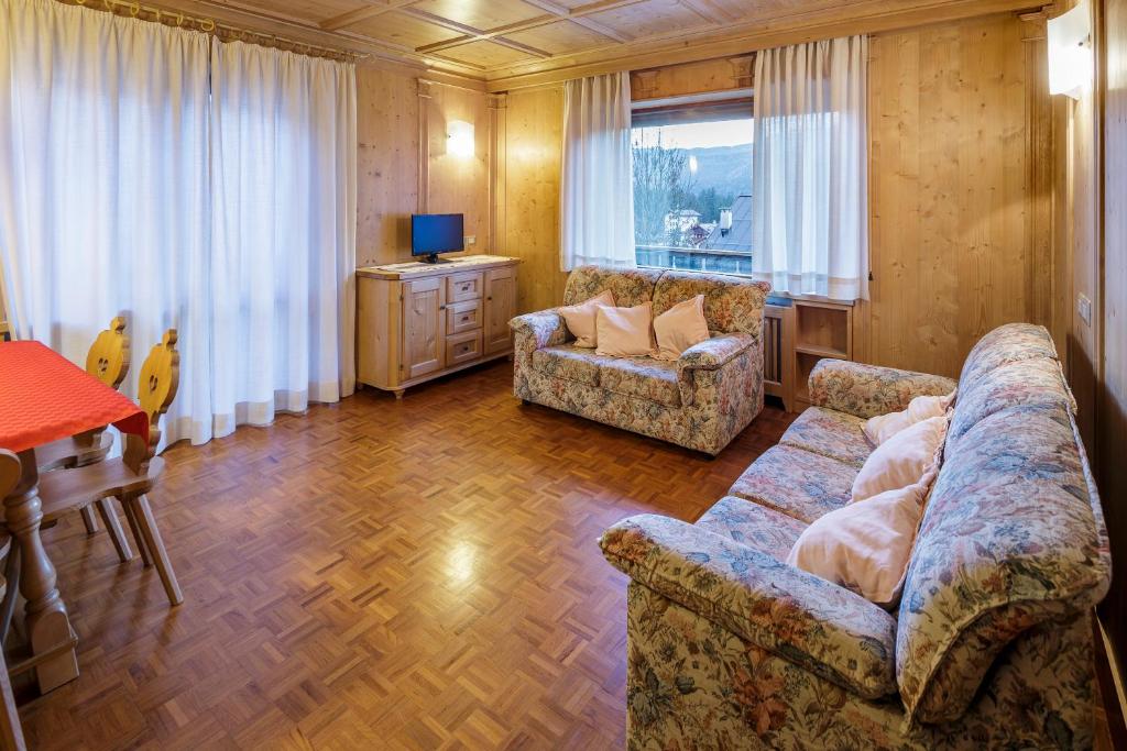 een woonkamer met een bank, een tafel en een televisie bij Villa Chiappuzza - Stayincortina in San Vito di Cadore
