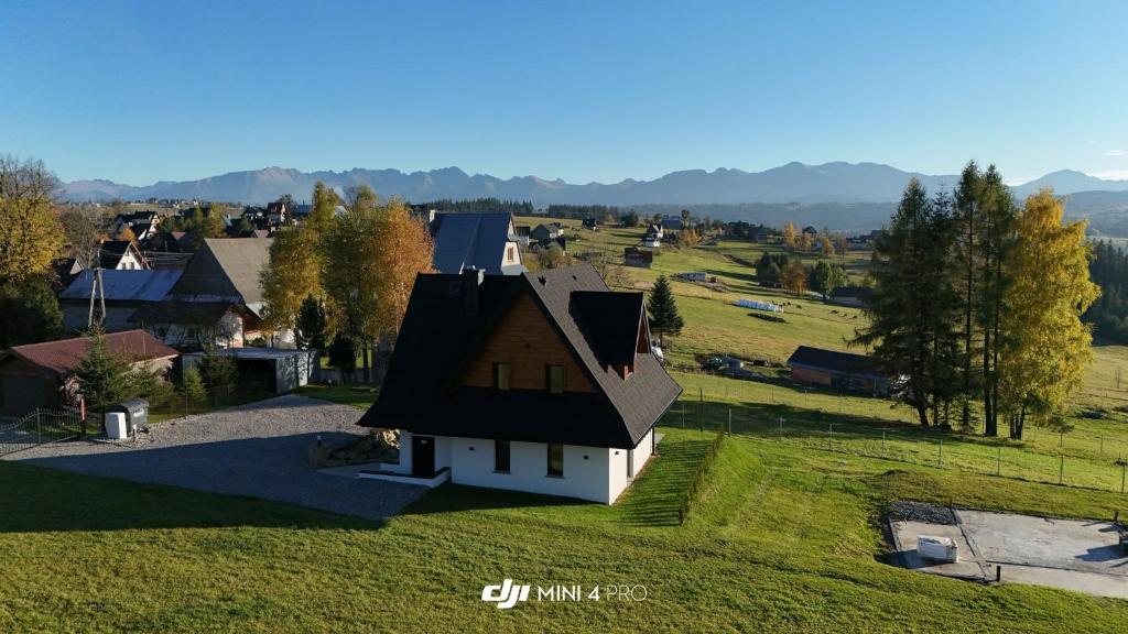 a small white house with a black roof on a green field at Na polanie in Czerwienne