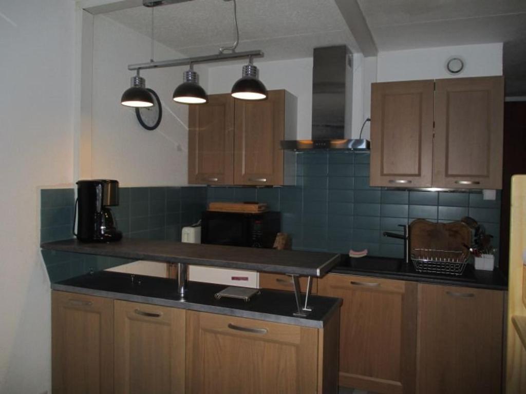 une cuisine avec des armoires en bois et un comptoir noir dans l'établissement Studio cosy avec parking, balcon sud, pied de pistes - FR-1-404-352, à La Mongie