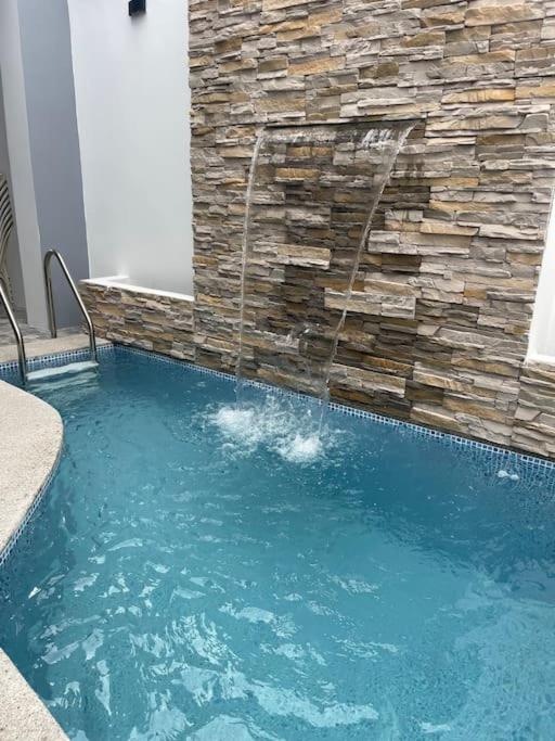 una piscina con cascada frente a una pared de piedra en Casa hermosa con piscina, en Salinas