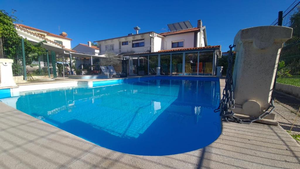 a large blue swimming pool in front of a house at Hostel Jardins de São Luís in Setúbal