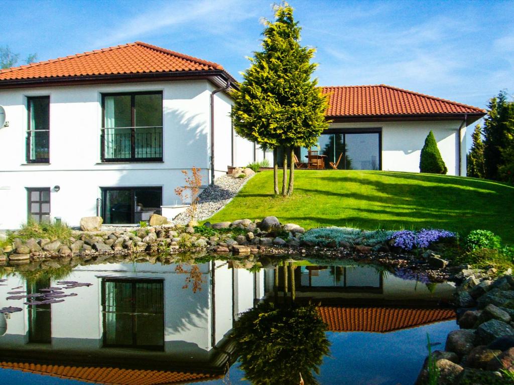 ein Haus mit einem Teich davor in der Unterkunft Gästehaus am Paradieshof in Schwerin