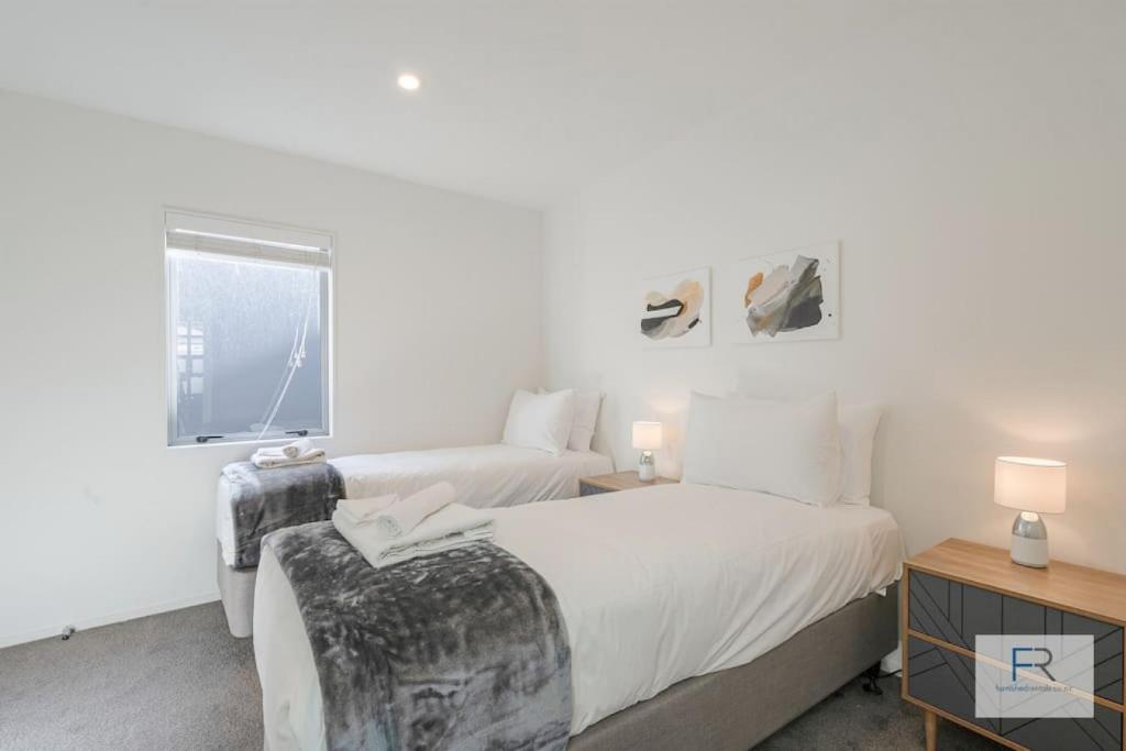 オークランドにあるExecutive city-fringe Townhouseの窓のある白い部屋にベッドが2つある