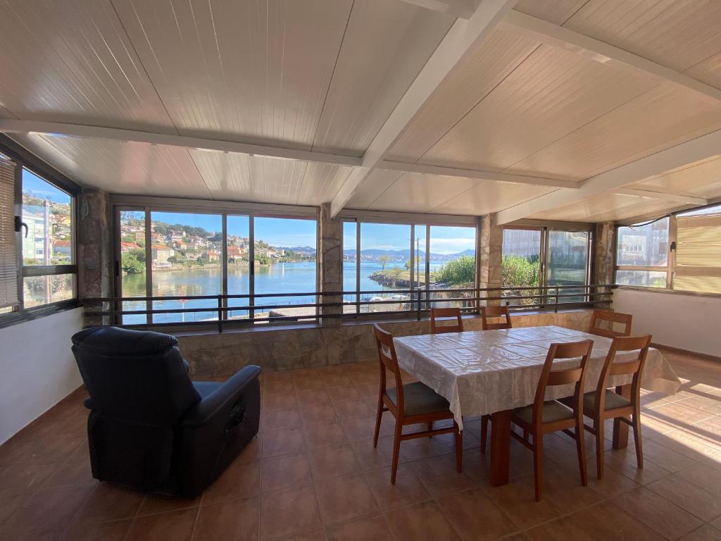 a dining room with a table and chairs and a view of the water at Despierta frente al mar en Moaña in Pontevedra