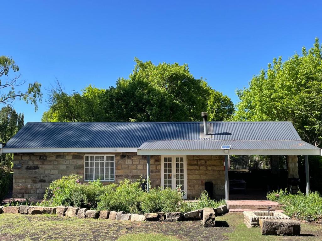 una casa in pietra con tetto in metallo di Periwinkle, Grove ,Acorn & Sage Cottages a Clarens