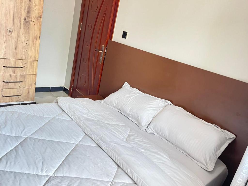a bed with white pillows on it in a room at Detail Apartment in Kira