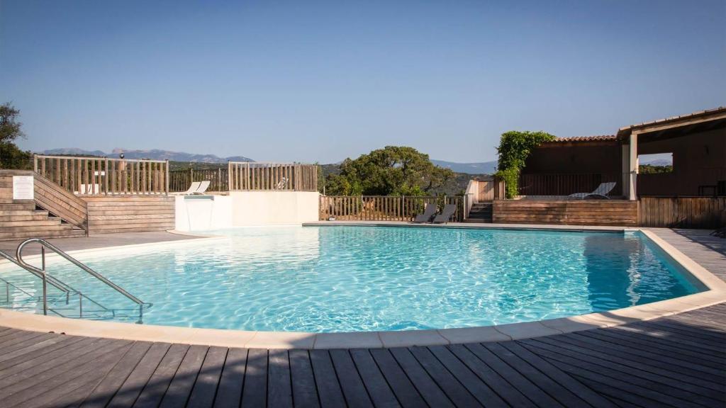 une grande piscine avec une terrasse en bois dans l'établissement Résidence Santa Giulia Park 1 avec piscine à proximité des plages, à Porto-Vecchio
