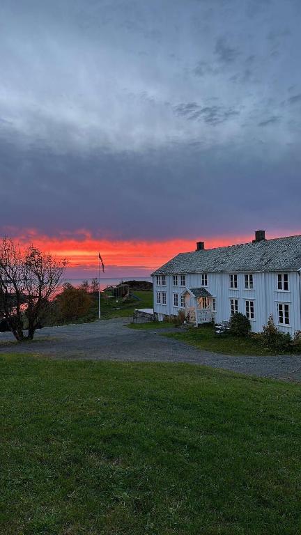 a white house with a sunset in the background at Sjønært småbruk in Bud