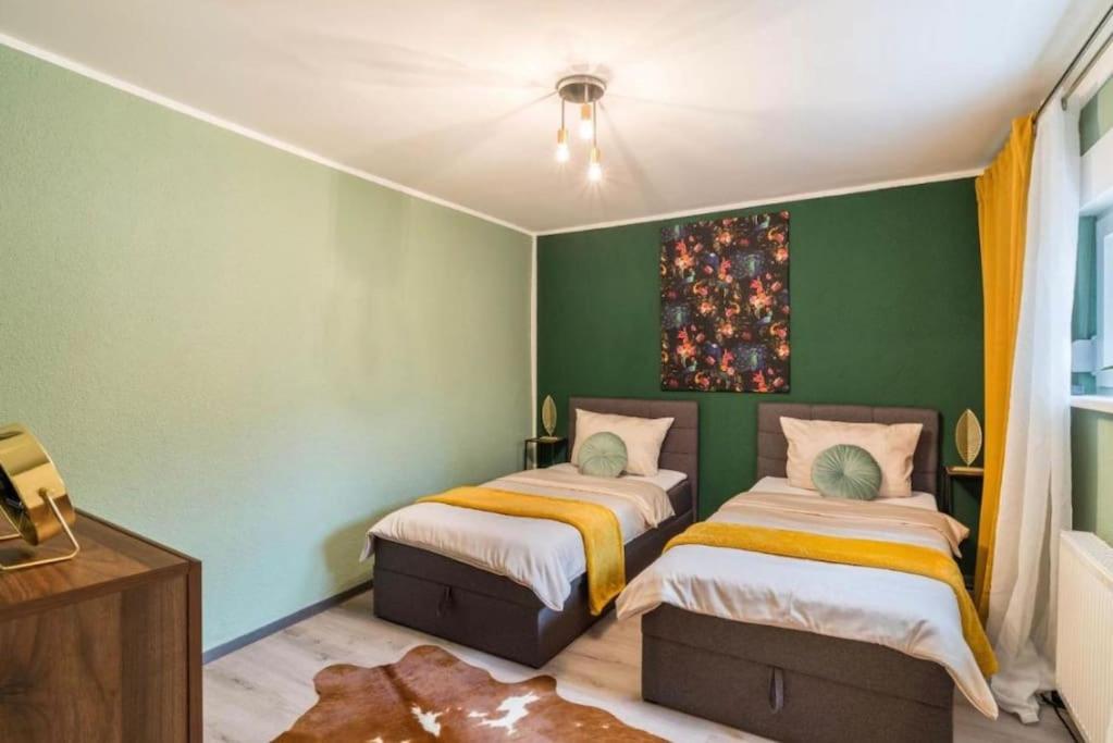 two beds in a room with green walls at Appartio - Apartment für 2 - Küche - WiFi - Altstadtlage in Worms