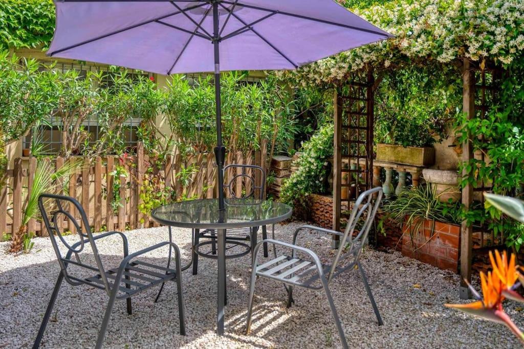 une table avec deux chaises et un parapluie violet dans l'établissement Centre-ville de Cannes 100 m mer, à Cannes
