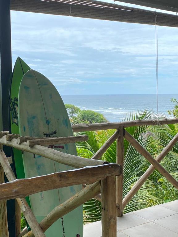 a surfboard sitting on top of a porch with the ocean at Surf Lodge El Carrizal-Punta Mango in La Periquera