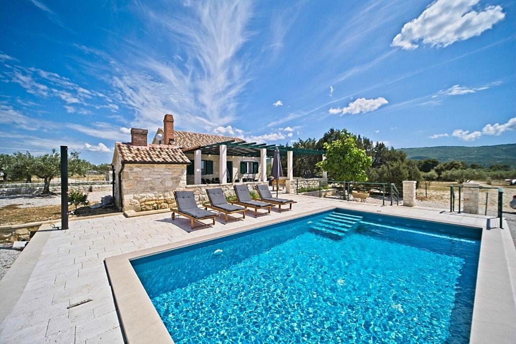 a swimming pool with two chairs and a house at House Diana in Pučišća