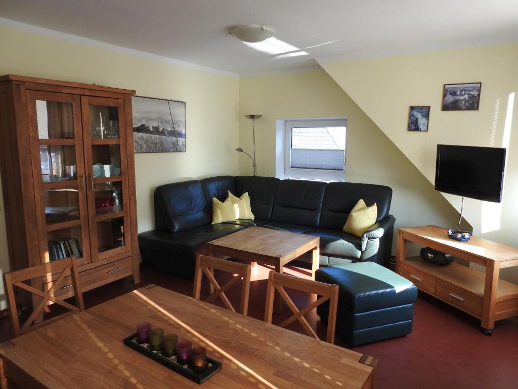 ein Wohnzimmer mit einer schwarzen Couch und einem Tisch in der Unterkunft Ferienwohnung Saalfeld in Schillig