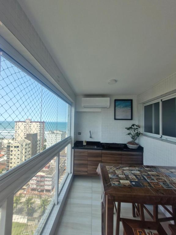 大普拉亚AP Elegante e luxuoso no Caiçara的阳台配有桌子和大窗户。