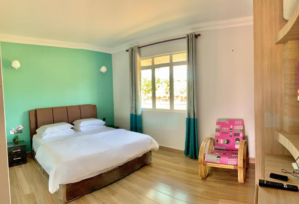 a bedroom with a bed and a window and a pink chair at Deluxe Room Mandahan Beach Garden in Kimanis