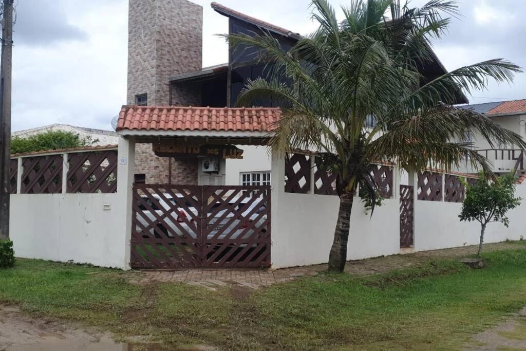 a house with a gate and a palm tree at Linda Casa Com Vista Pro Mar in Ilha Comprida