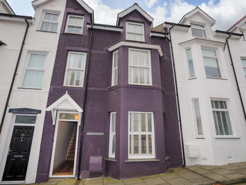 a purple house with white windows on a street at Maelgwyn in Criccieth