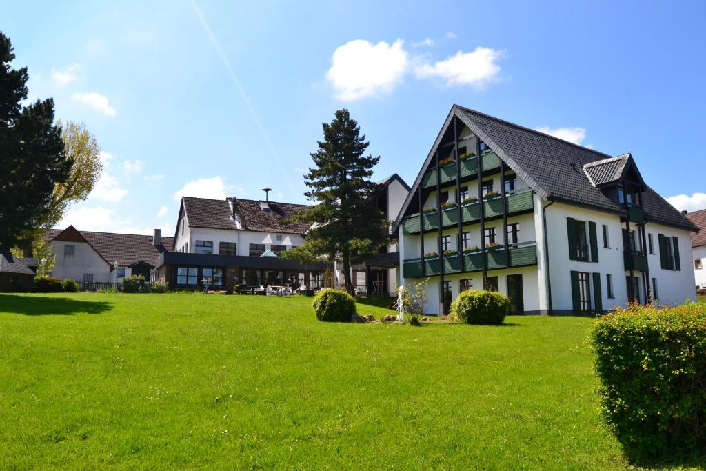 a large white house with a green lawn at Gasthof Spelsberg in Altena